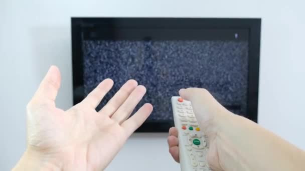 Hand mit TV-Fernbedienung vor dem Bildschirm mit weißem Rauschen darauf - Abstimmung der Fernsehkanäle und Verbindungsprobleme — Stockvideo