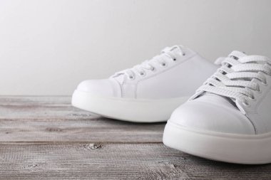 Ahşap arka planda beyaz deri spor ayakkabılar..