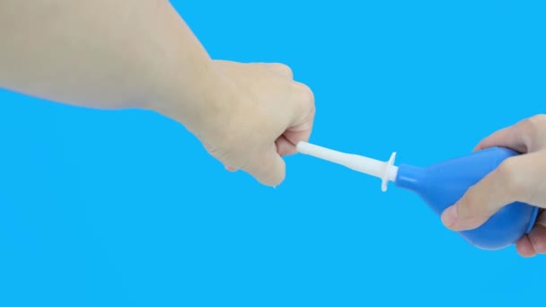Ruka s modrým klystýrem čerpání, vstřikování vody na modré pozadí, čištění klystýr efekt simulace — Stock video