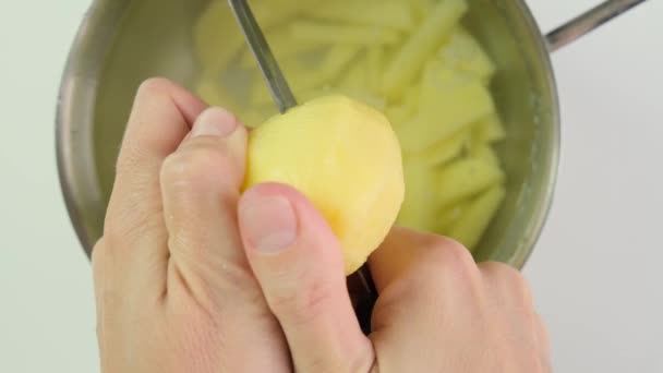 Γυναικεία χέρια που κόβουν ακατέργαστη αποφλοιωμένη πατάτα με μαχαίρι κοντά — Αρχείο Βίντεο