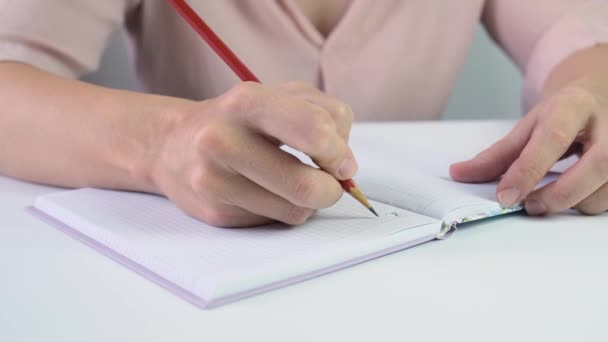 Vrouw met rood potlood en het schrijven van iets in een notebook, doel instelling en planning concept — Stockvideo