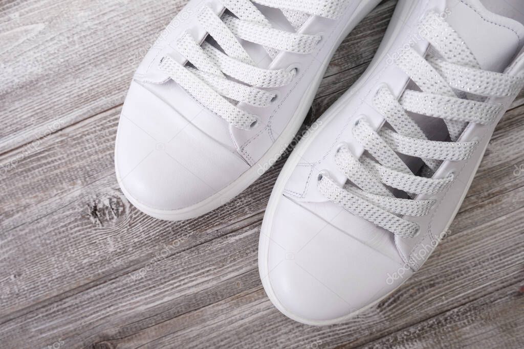 White leather casual sneakers on wooden background