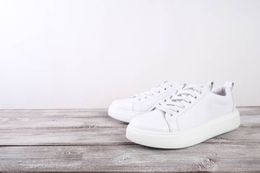Ahşap arka planda beyaz deri spor ayakkabılar, kopyalama alanı