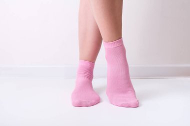 Kadın bacakları pembe çizgili düz pamuklu çoraplar giyiyordu. Klasik tarzda. Lastik bant beyaz arka planda duruyordu.