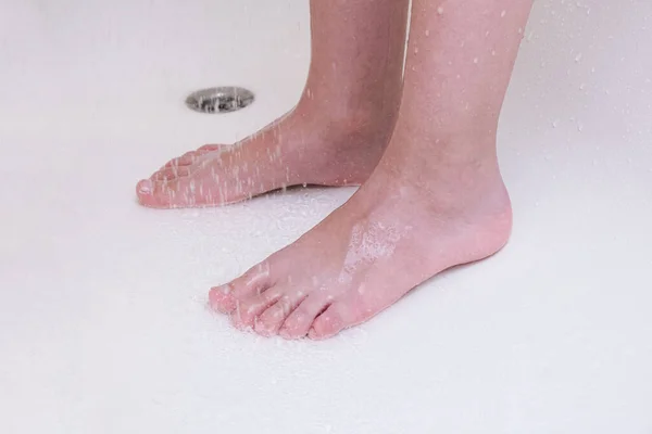 Los pies de un niño tomando una ducha, un niño lavando las piernas en un baño, higiene y rutina de limpieza — Foto de Stock