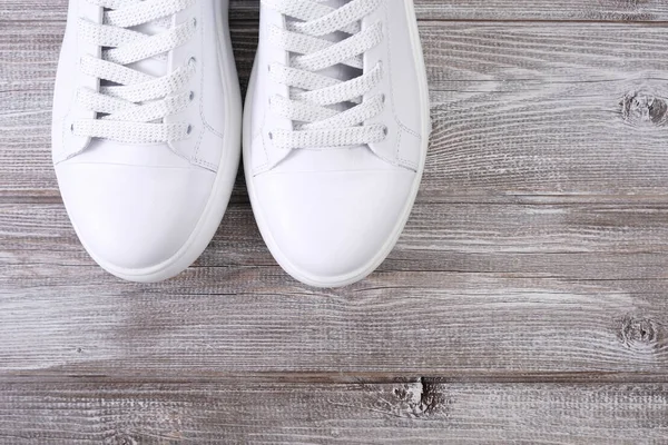 Zapatillas casual de cuero blanco sobre fondo de madera con espacio para copiar —  Fotos de Stock