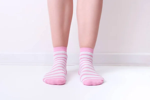 Woman female legs wearing pink and white striped plain cotton socks of classic style with elastic band standing against white background — Stock Photo, Image