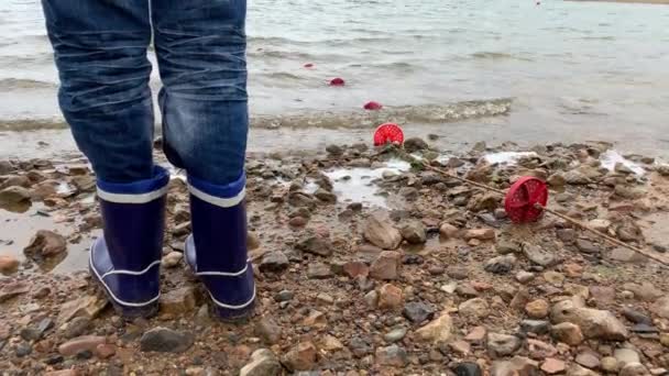 Πόδια Ενός Αγοριού Μπλε Λαστιχένιες Μπότες Στέκεται Μια Λίμνη Άμμο — Αρχείο Βίντεο