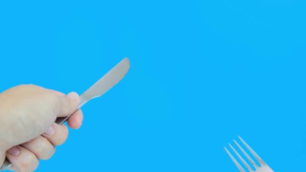 一个人在蓝色背景下拿着叉子和小刀 第一个人的饥饿概念 — 图库视频影像