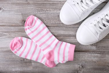 Beyaz deri spor ayakkabılar ve ahşap arka planda pembe ve beyaz çizgili pamuklu çoraplar, yürüyüş ve egzersiz için bir set..