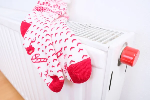 Calcetines blancos y rojos de Navidad que cuelgan del radiador de calor central caliente, humor de la casa de vacaciones de invierno — Foto de Stock