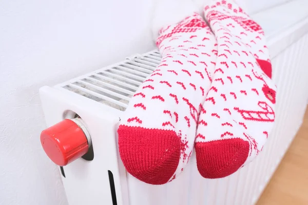 White and red christmas socks hanging on warm central heat radiator, winter holiday home mood