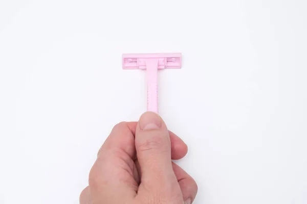 A hand holding pink disposable plastic woman razor blade for shaving, body care and unwatred hair removing on legs, armpits and face against white background — Stock Photo, Image