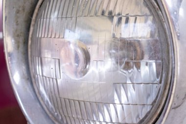 Paslı eski bir arabanın ön farları fotokopi alanıyla kaplıdır.