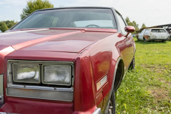 Um farol de um carro velho retro vermelho fechar em um ferro-velho jarda, nostalgia para os velhos tempos — Fotografia de Stock
