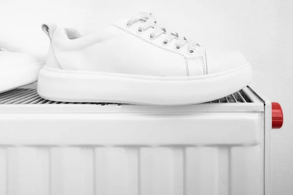 Zapatillas de deporte de cuero blanco que se secan en una rasiator calor central después de mojarse o wasing y eliminar la suciedad — Foto de Stock