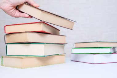 Bir el kitap yığınından bir kitap alıyor, kitap seçiyor ve okumak için kitap seçiyor.