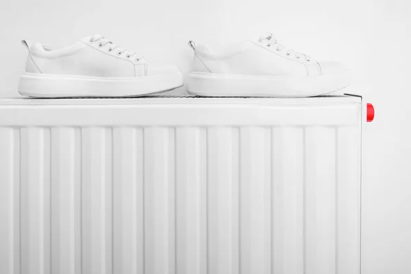 Белые кожаные кроссовки, высыхающие на центральном нагревателе после промокания или обтирания и удаления грязи — стоковое фото