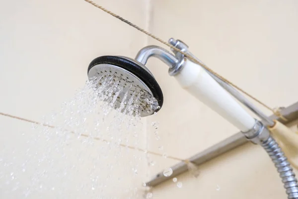 Agua que fluye de un cabezal de ducha viejo con mango de cerámica con cal necesita ser reemplazado o descalcificado — Foto de Stock