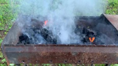 Barbeküde yanan ateş, kül ve gri uçan duman, alevler ve kırsal mangal dumanı.
