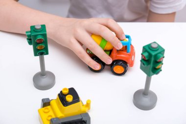 Beyaz bir masada oyuncak araba oynayan bir çocuk..