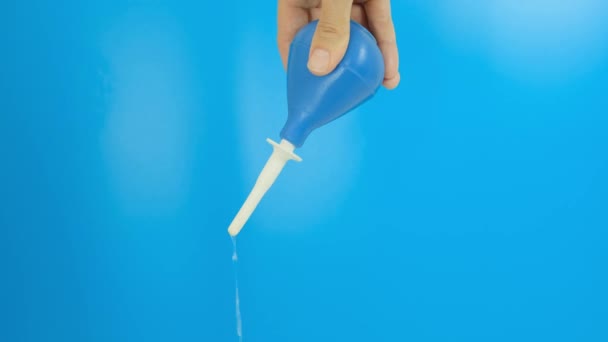 Tangan dengan enema biru memompa, mengkompresi, meremas dan menyuntikkan air pada latar belakang biru — Stok Video