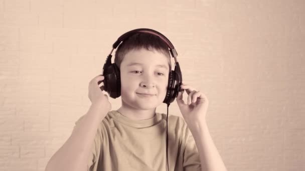 Хлопчик в навушниках слухає музику, трясе і киває головою вчасно до музики, вінтажний тонований і стилізований — стокове відео