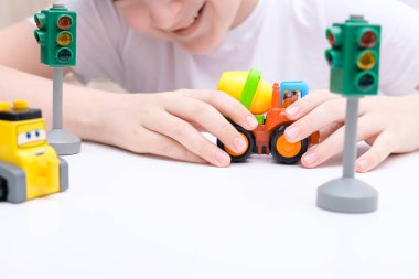 Beyaz bir masada oyuncak araba oynayan bir çocuk.