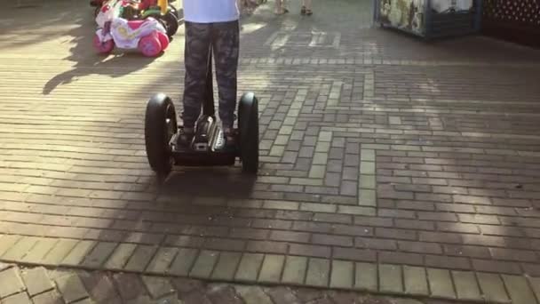Chlapec jedoucí na segway ve veřejném městském parku, půjčovna elektrické kolové dopravy — Stock video