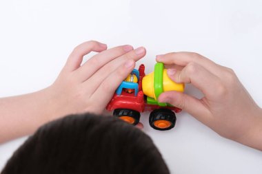 Beyaz bir masada oyuncak araba oynayan bir çocuk.