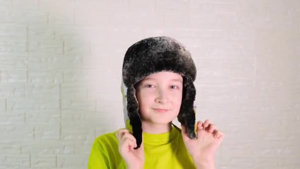 Um menino vestindo um chapéu quente de inverno com abas de orelha — Vídeo de Stock