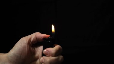 Kara gece arka planında çakmak olan el alevi. Alev yaratmak için taşınabilir cihaz.