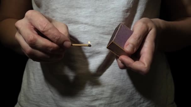 A person, woman lighting match in the dark, hold burning matchstick and a match box in the dark — Stock Video