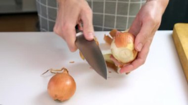 Pirzola yapmak için sarı soğan soyan, ev yapımı yemek pişiren bir kadın.