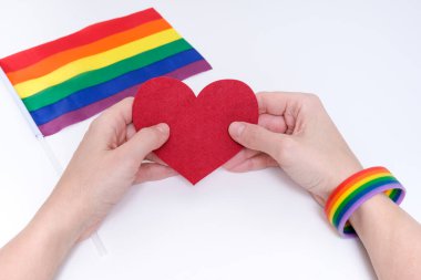 Igbtq gökkuşağı bileziği takan bir kadın kalp taşıyor.