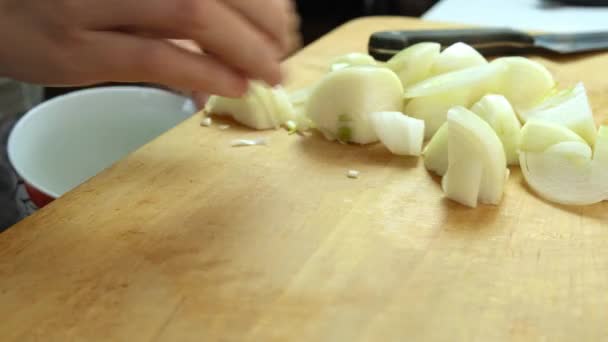 Een hand vegen gesneden ui van een houten plank naar een kom close-up, koken zelfgemaakt voedsel concept — Stockvideo