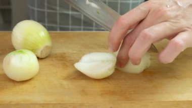 Kadın bir şef yemek yaparken bıçakla soğan doğruyor, ev yapımı yemekler yapıyor.