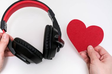 Müzik kulaklığı tutan eller ve aşk müziği konsepti olarak kırmızı kalp.