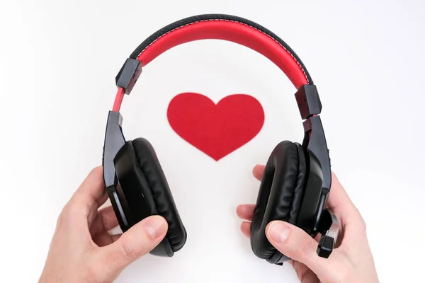 Hands holding stereo headphones and a red heart as a love music concept — Stock Photo, Image