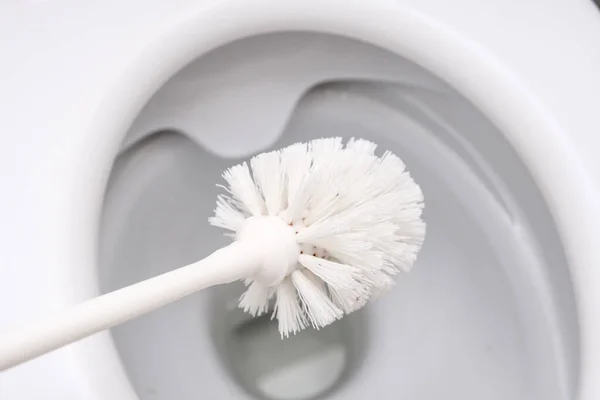 White toilet brush ready to clean toilet bowl, concept for house cleaning and household duties — Stock Photo, Image