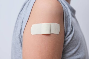 Aşıdan sonra üzerinde bandaj bandı olan bir çocuğun kolu. Covid aşısı, çocuklar ve gençler için sağlık hizmetleri