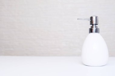 Beyaz sıvı sabun, vücut losyonu. Banyonun arka planında fotokopi alanı olan bir losyon makinesi.