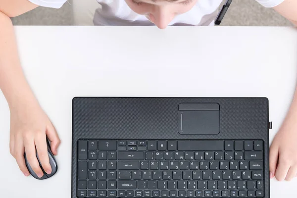 Un niño usando el ordenador portátil en una mesa blanca, vista superior —  Fotos de Stock