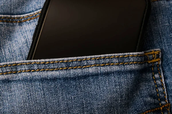 Uno smartphone nero nella tasca di blue jeans, concetto di comunicazione delle persone — Foto Stock