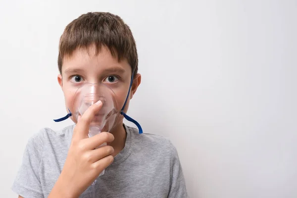 Un niño sosteniendo en una cara una mascarilla de oxigeno, neumonía y prevención de enfermedades pulmonares, inhalación de drogas a los pulmones, espacio para copiar —  Fotos de Stock