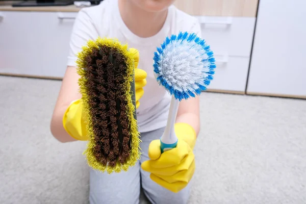 Ein Kind in gelben Gummihandschuhen zeigt Büstenhalter für die Hausreinigung, Teppich von Staub und Flecken — Stockfoto