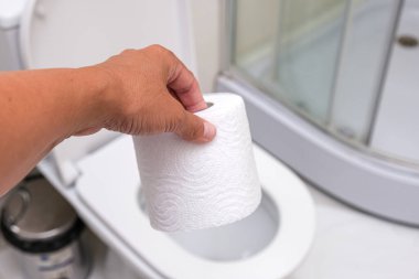 Beyaz rulo tuvalet kağıdı tutan bir el karın ağrısı ve sindirim sorunları kavramı.