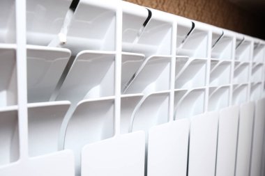 Oturma odasındaki beyaz kalorifer ısıtıcısı, evdeki konfor ve sıcaklık için merkezi ısıtma sistemi.