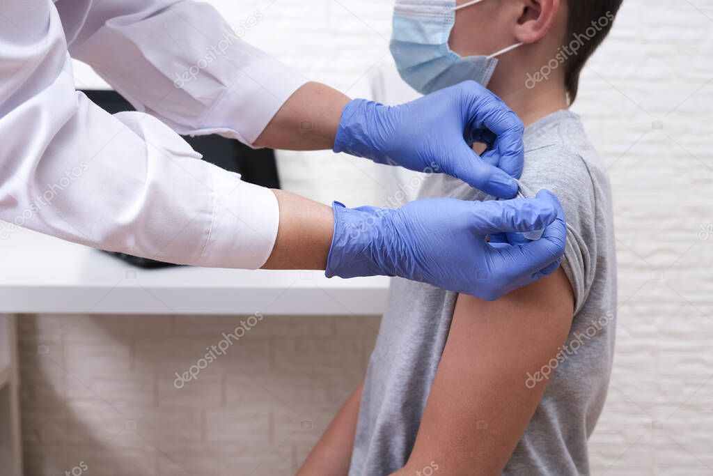 A boy at school getting vaccinated from covid-19, receiving a vaccine from sars-cov-2 virus