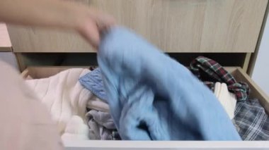 Kadın eli çekmecede doğru şeyi bulmaya çalışıyor. Kıyafetleri dağınık, kıyafetleri dağınık, kıyafetleri dağınık.